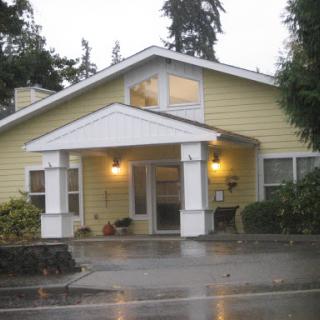 A cozy yellow house with a welcoming front porch, captured on a rainy day.