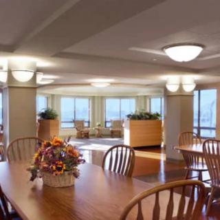 A well-lit dining area with wooden tables and chairs, decorated with floral arrangements and large windows providing a view.
