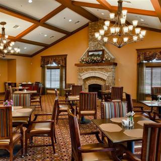 Elegant dining room with a rustic fireplace and classic chandeliers.