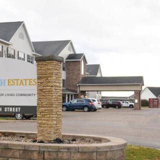 A residential area with a row of buildings, a parking lot, and a sign under an overcast sky.