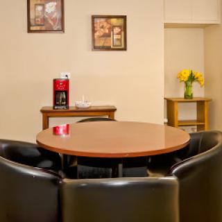 A cozy dining area featuring a round table surrounded by black chairs, with decorative artwork on the walls and a small vase of flowers.