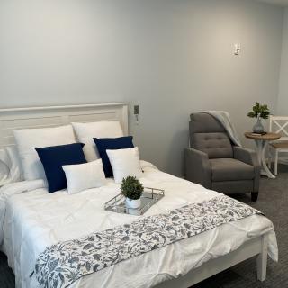 A modern and cozy bedroom with a neatly made bed, decorative pillows, and a small plant on a tray.