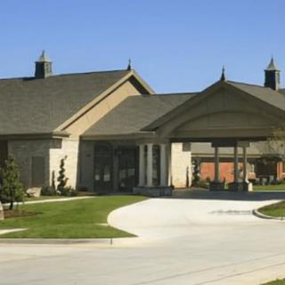 A modern building with a covered entrance and curved driveway under a clear blue sky.