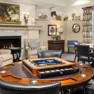A cozy living room featuring a game table, fireplace, and elegant interior decor.