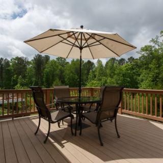 A patio set with an umbrella on a wooden deck overlooking a lush green landscape.