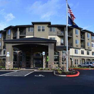 A modern hotel with a flagpole in the parking area.