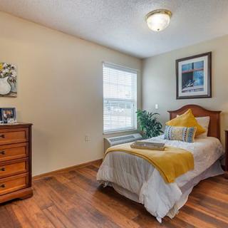 A cozy bedroom with a single bed, wooden flooring, and tasteful decor.