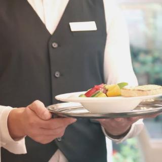 A waiter carrying a tray with food in a restaurant setting.