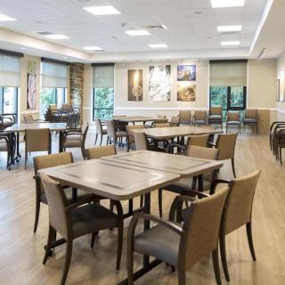 A modern dining area with neatly arranged tables and chairs, featuring bright lighting and a spacious layout.