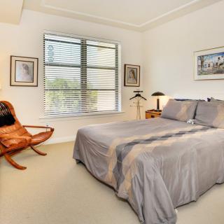 A cozy bedroom with a double bed, artwork on the walls, and a comfortable chair by the window.