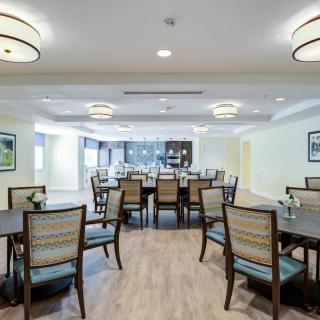 A spacious dining area with neatly arranged tables and chairs, illuminated by modern ceiling lights.