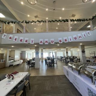 A spacious dining area beautifully decorated for a holiday celebration, featuring a buffet setup and festive banners.