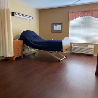 A simple hospital room featuring a bed, curtains, and a window.