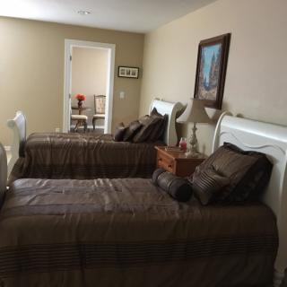 A cozy bedroom featuring two twin beds with brown bedding and decorative pillows, enhanced by a painting and a lamp.