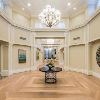 A luxurious foyer with a grand chandelier, elegant wood flooring, and decorative elements.