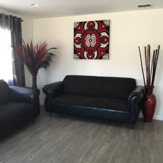 A modern living room with dark sofas, decorative wall art, and accent vases.