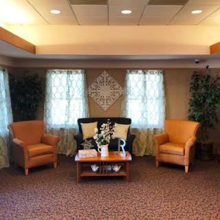 A cozy waiting area featuring comfortable armchairs, a coffee table, and natural light streaming through the curtains.