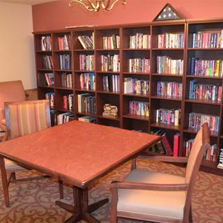 A cozy library reading room with bookshelves, a table, and chairs.