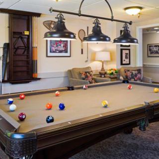 A stylish game room featuring a classic pool table with overhead lighting.