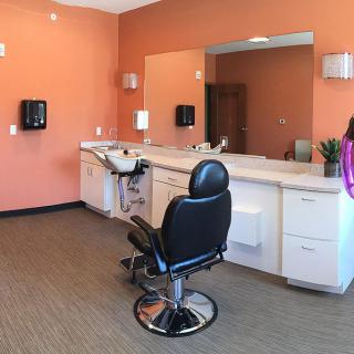 A modern hair salon interior with a barber chair, mirror, and sink.