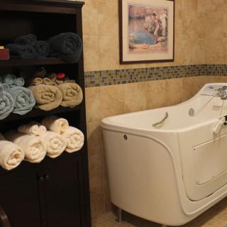 A neatly organized bathroom with rolled towels and a modern bathtub.
