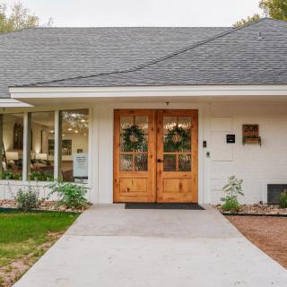 A modern residential house entrance with double wooden doors adorned with wreaths.