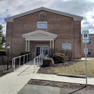 A brick building featuring a ramp for handicap accessibility, set against a cloudy sky.