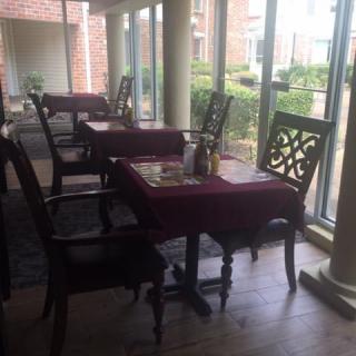 Cozy restaurant interior with tables and chairs by the window, offering a pleasant daytime view.
