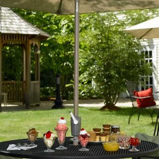 A garden patio scene with a table under an umbrella, displaying various desserts and snacks.