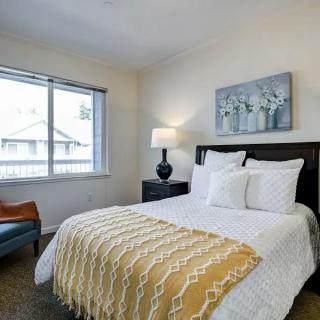 A cozy bedroom with a neatly made bed, a lamp on the bedside table, and artwork above the headboard.