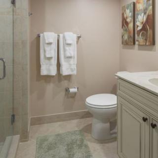 A well-organized bathroom featuring a toilet, sink with cabinet, and neatly hung towels.