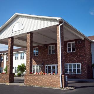 Brick building with a large covered entrance on a sunny day.