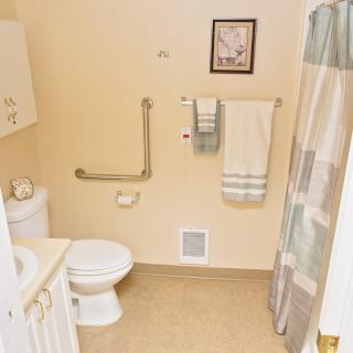 A bathroom featuring a toilet, sink, and shower with a curtain, along with towels and wall art.