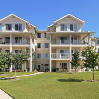 A modern apartment building with balconies and a spacious lawn area.