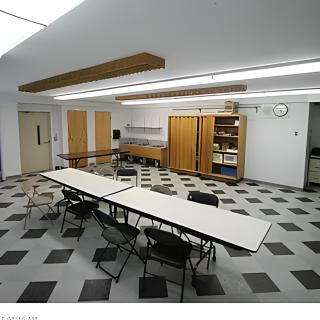 An empty classroom or meeting room with tables arranged in a U-shape and chairs around them.