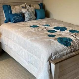 A well-decorated bed with a floral-patterned comforter and several decorative pillows.