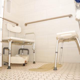 A bathroom designed for accessibility, featuring shower chairs and grab bars for safety.
