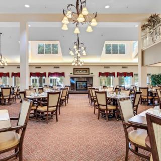 A spacious dining area with elegant chandeliers and neatly arranged tables and chairs.