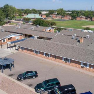 Aerial view of a school building with an adjacent parking lot and grassy field.