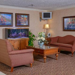 A cozy living room with sofas, a wooden table, artwork on the walls, and a fish tank.