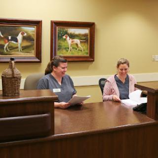 Two employees working at a reception desk in an office setting.
