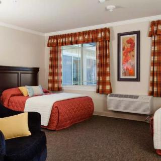 A cozy hotel room featuring twin beds, patterned curtains, and a decorative painting on the wall.