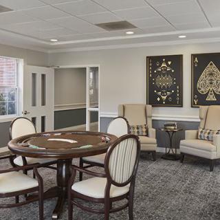 A stylish meeting room featuring a poker table, comfortable chairs, and decorative artwork on the walls.