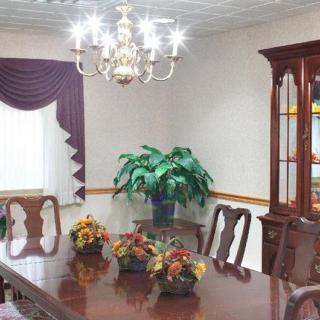 A cozy dining room with a wooden table set, chairs, and a chandelier, complemented by decorative flowers and an indoor plant.