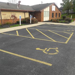 A view of a brick building with a designated handicapped parking spot in the lot.