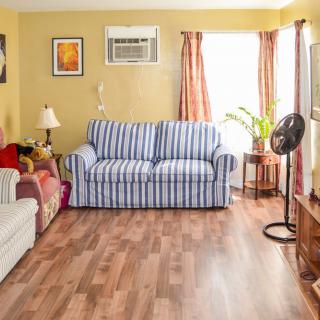 A cozy living room with a striped couch, wooden flooring, and warm lighting.