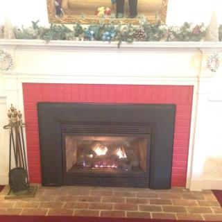 A cozy indoor fireplace with a decorative mantel and burning firewood.