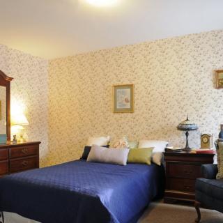 A cozy bedroom with classic furniture and a blue bedspread.