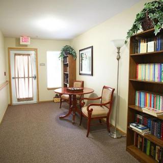 A cozy hallway with a bookshelf, table, and chairs for reading.