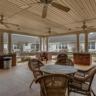 A spacious outdoor patio area with wicker furniture and ceiling fans, providing a comfortable relaxation space.
